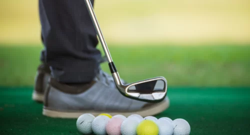 Close up of golfers shoe next to many different golf balls