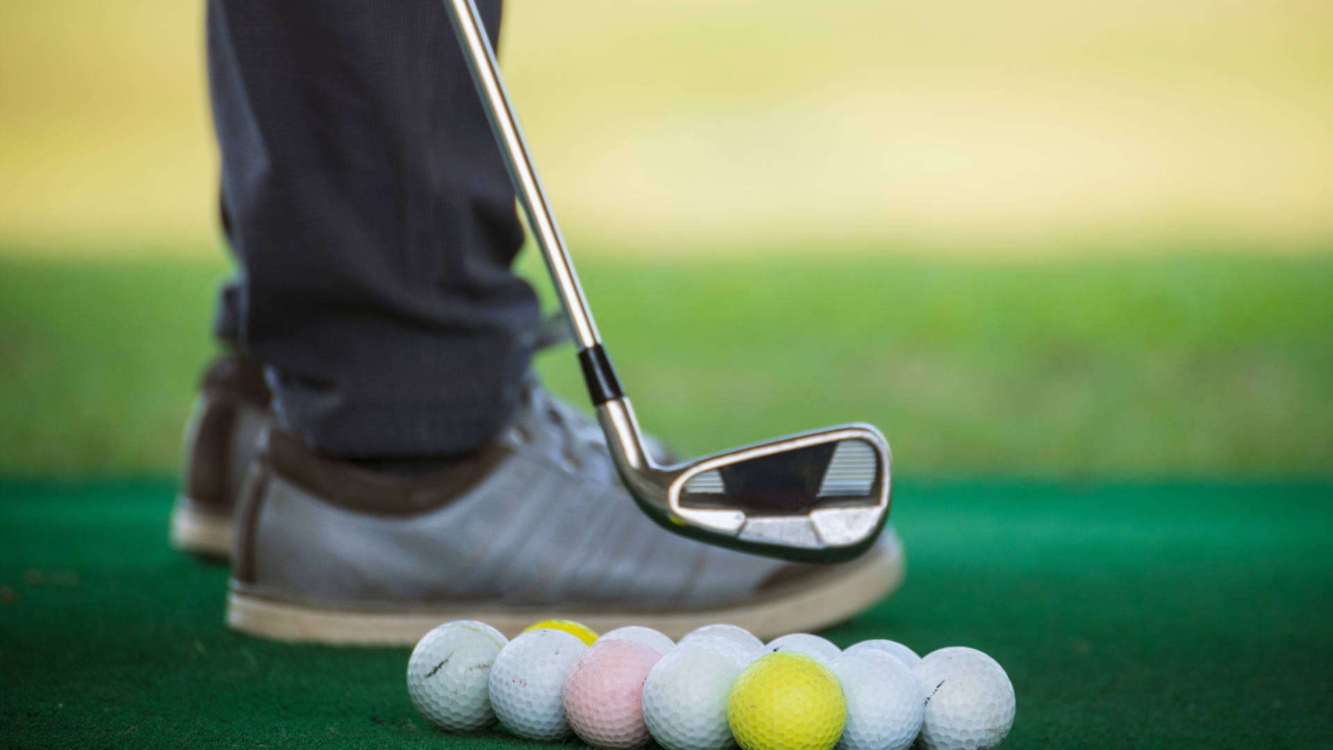 Close up of golfers shoe next to many different golf balls