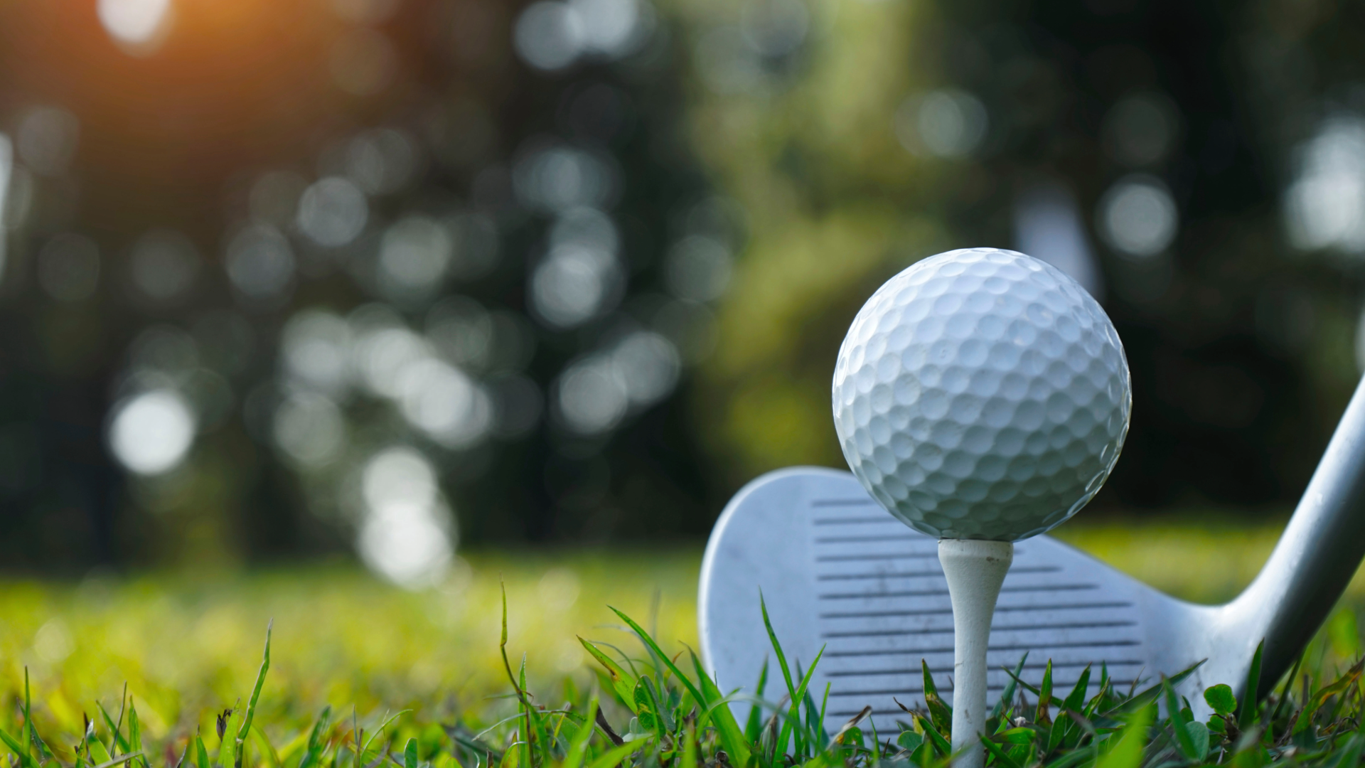 Golf ball teed up and a putter lining up the shot