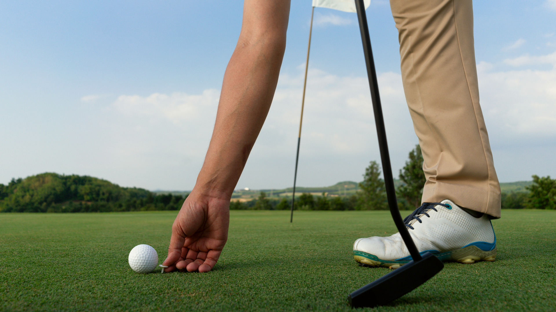 Golfer placing a ball on the greens